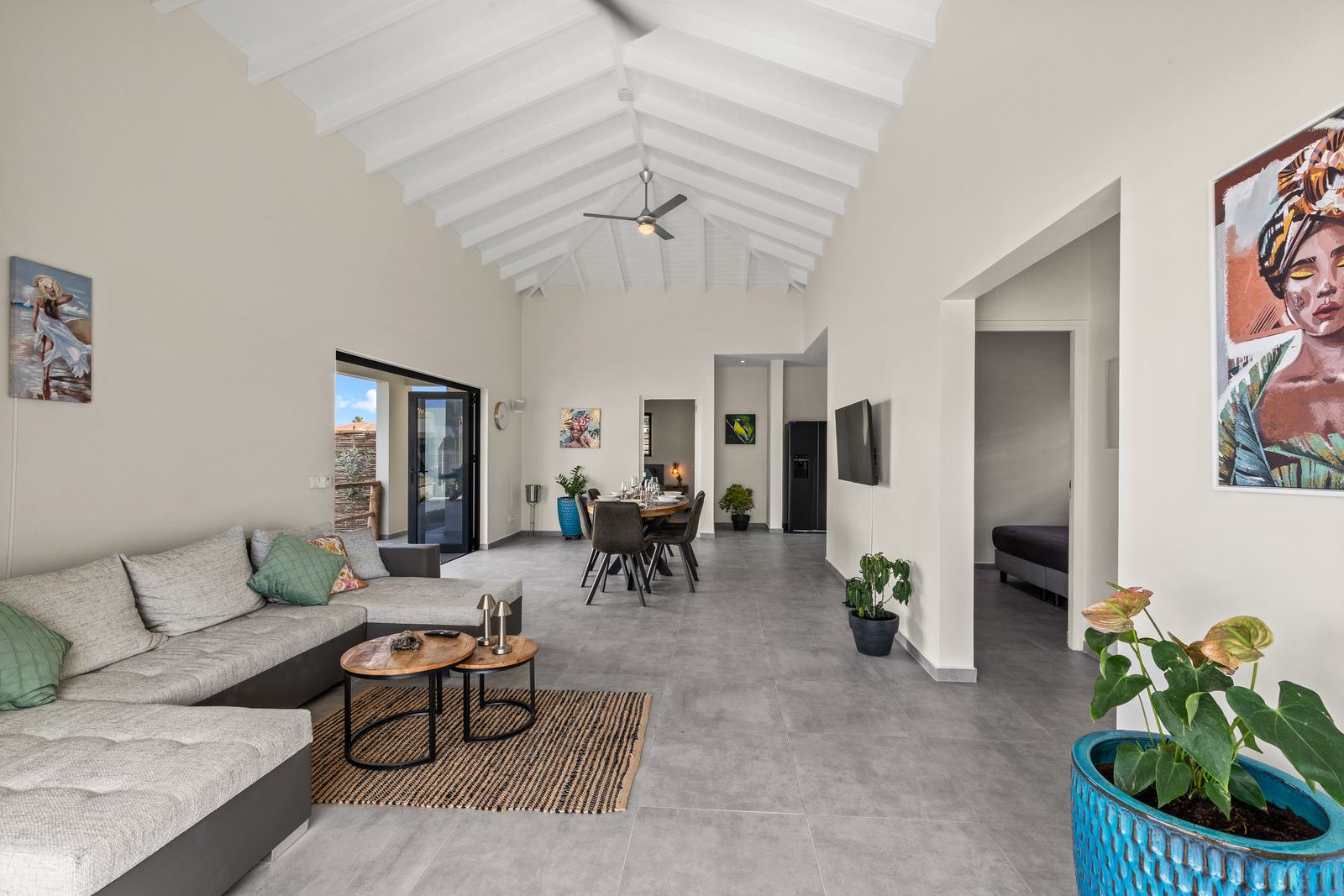 Ruime open woonkamer met hoog wit plafond en loungebank